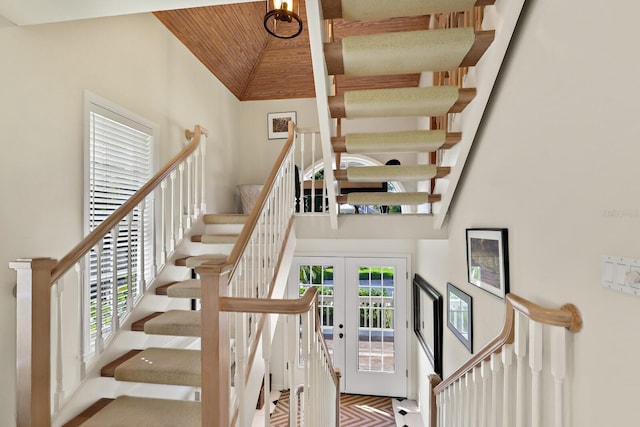 stairway with french doors, wooden ceiling, and a high ceiling