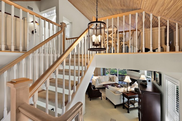 stairway featuring carpet floors, an inviting chandelier, wood ceiling, and high vaulted ceiling