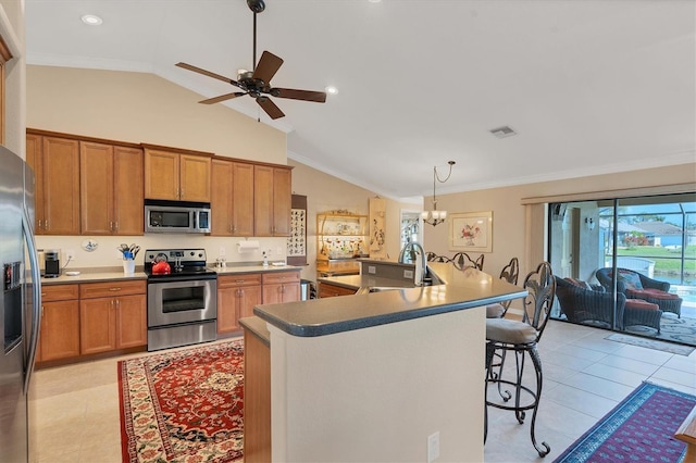 kitchen featuring pendant lighting, a breakfast bar, appliances with stainless steel finishes, ornamental molding, and a center island with sink