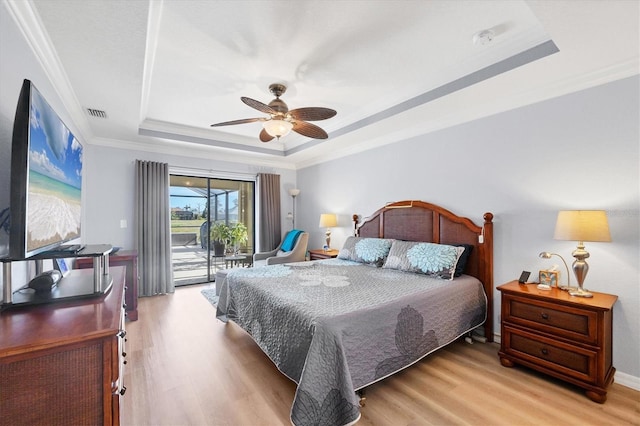 bedroom featuring crown molding, a tray ceiling, access to outside, and light hardwood / wood-style floors