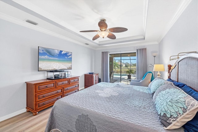 bedroom featuring crown molding, light hardwood / wood-style flooring, ceiling fan, access to outside, and a raised ceiling