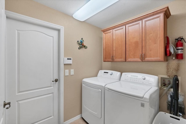 clothes washing area with cabinets and washer and clothes dryer