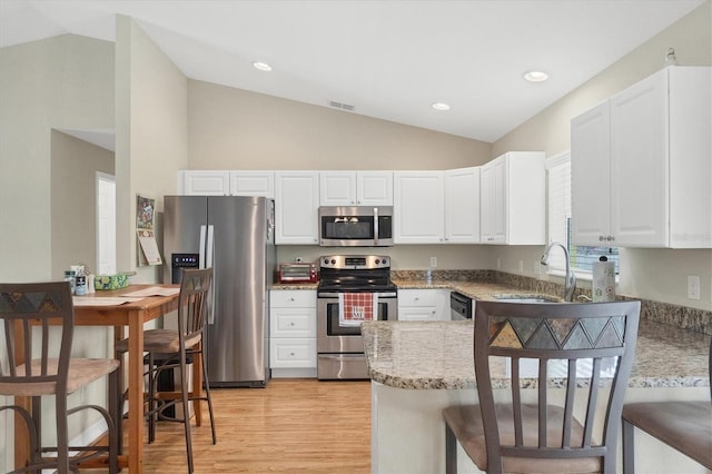 kitchen featuring appliances with stainless steel finishes, white cabinetry, sink, light stone counters, and kitchen peninsula