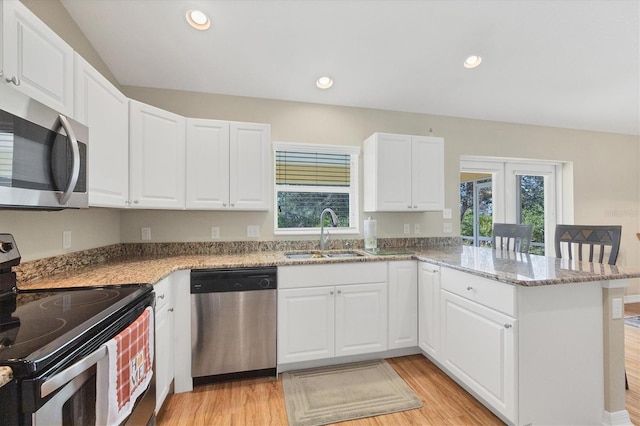 kitchen featuring white cabinetry, sink, kitchen peninsula, stainless steel appliances, and light stone countertops