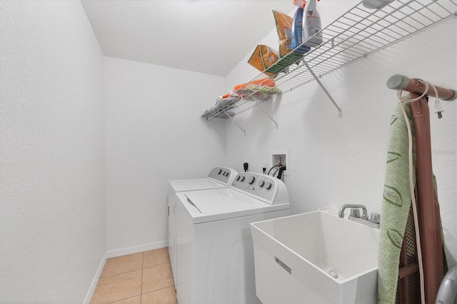 laundry room with light tile patterned flooring, separate washer and dryer, and sink