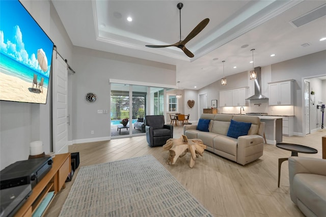 living room featuring a barn door, a towering ceiling, ceiling fan, and light hardwood / wood-style floors