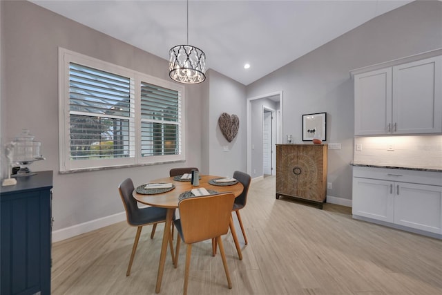 dining area featuring lofted ceiling, an inviting chandelier, and light hardwood / wood-style floors