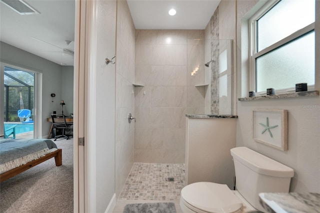 bathroom with tiled shower, ceiling fan, and toilet