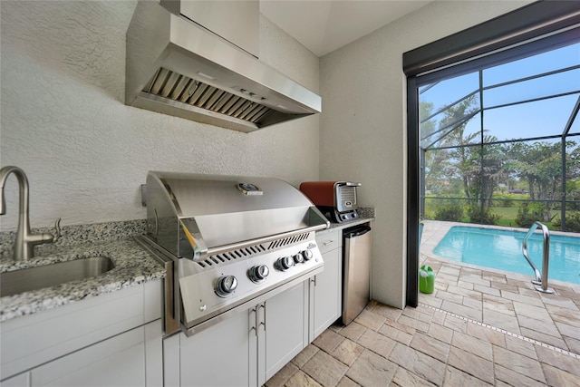 exterior space featuring sink, grilling area, glass enclosure, and exterior kitchen