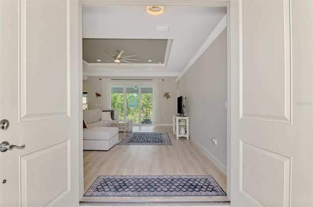 interior space featuring crown molding, ceiling fan, a raised ceiling, and light hardwood / wood-style flooring