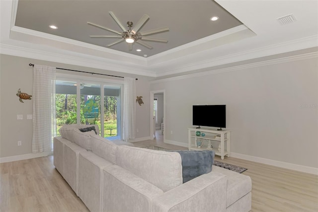 living room featuring crown molding, light hardwood / wood-style flooring, a raised ceiling, and ceiling fan