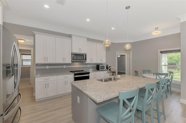 kitchen with white cabinetry, appliances with stainless steel finishes, sink, and pendant lighting