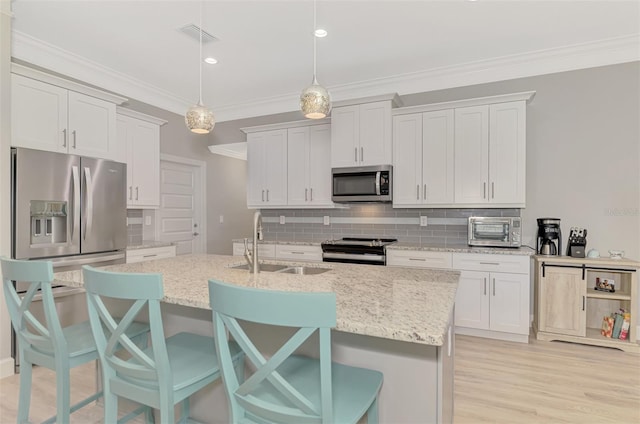 kitchen featuring hanging light fixtures, sink, white cabinets, and appliances with stainless steel finishes