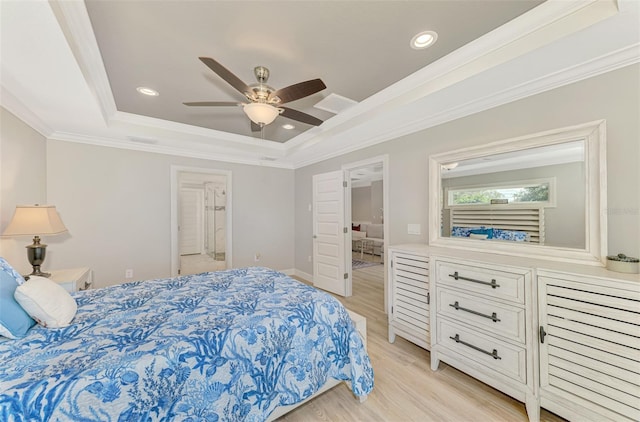 bedroom with ornamental molding, connected bathroom, a raised ceiling, and light hardwood / wood-style flooring