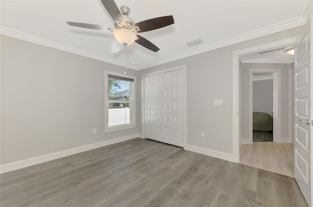 unfurnished bedroom featuring crown molding, ceiling fan, light hardwood / wood-style floors, and a closet