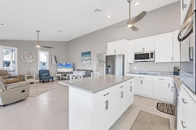 kitchen featuring visible vents, white cabinets, appliances with stainless steel finishes, open floor plan, and a center island