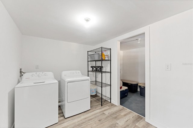 clothes washing area with light wood-style floors, washing machine and dryer, and laundry area