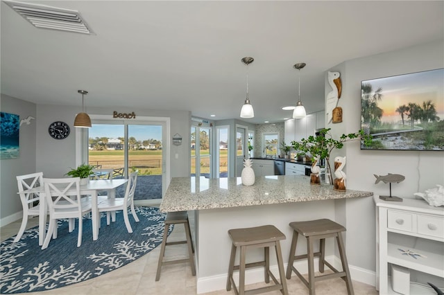 kitchen featuring light stone countertops, decorative light fixtures, a kitchen breakfast bar, and kitchen peninsula