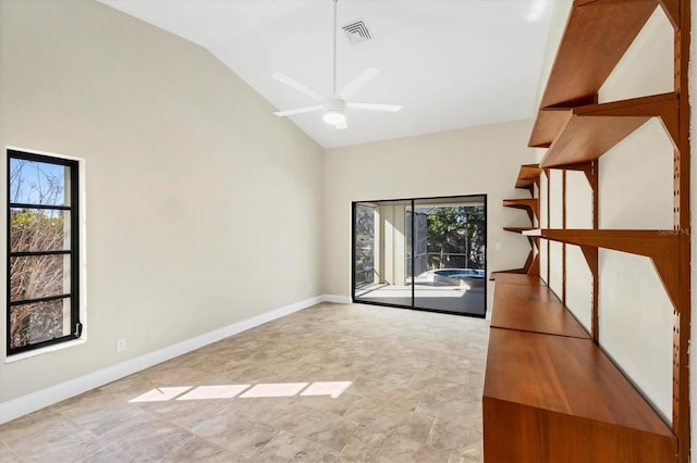 empty room with ceiling fan, plenty of natural light, and high vaulted ceiling