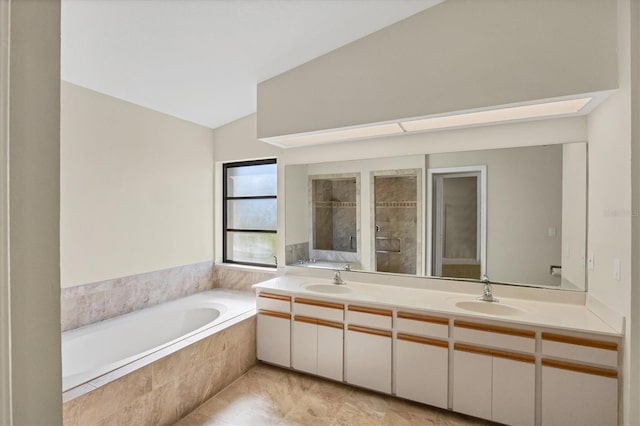 bathroom with vanity, lofted ceiling, and tiled bath