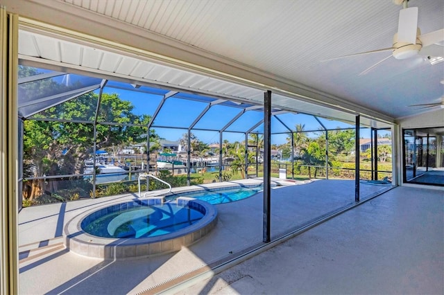 view of swimming pool featuring ceiling fan, a patio, a water view, glass enclosure, and an in ground hot tub