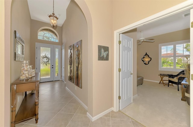 tiled entrance foyer with a high ceiling and a wealth of natural light