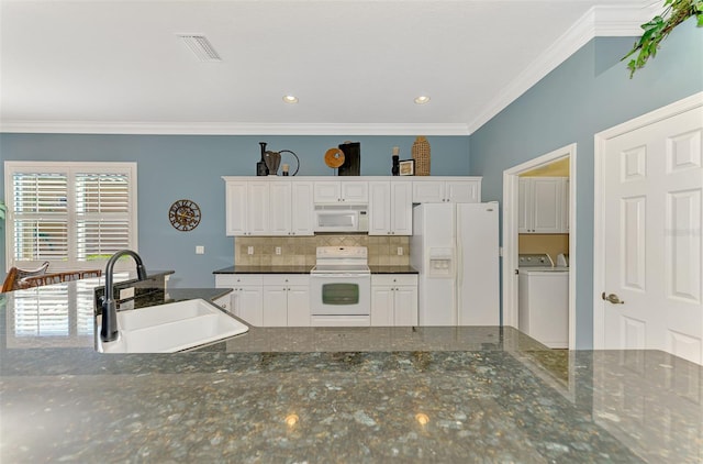 kitchen with washing machine and dryer, sink, white cabinets, and white appliances