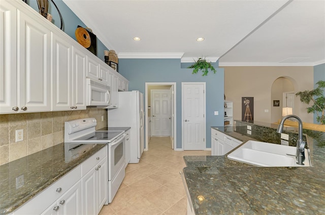 kitchen featuring tasteful backsplash, sink, dark stone countertops, white cabinets, and white appliances