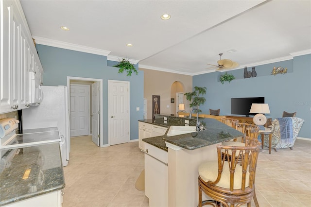 kitchen featuring a kitchen island with sink, sink, ornamental molding, and white cabinets