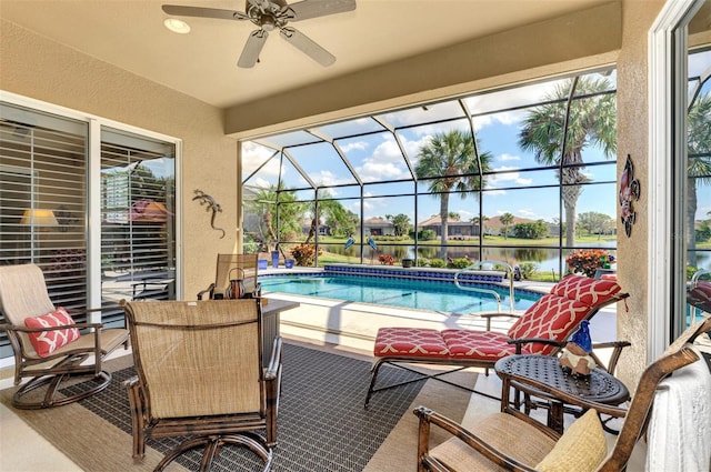 view of pool with a lanai, a patio, ceiling fan, and a water view