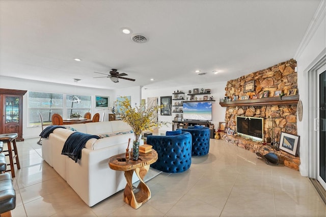 living room with light tile patterned flooring, ceiling fan, a fireplace, and crown molding