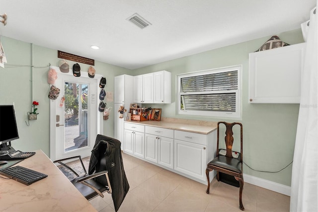 kitchen with white cabinetry, light tile patterned floors, and light stone counters