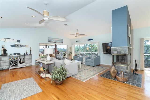 living room with ceiling fan, lofted ceiling, a fireplace, and light hardwood / wood-style floors