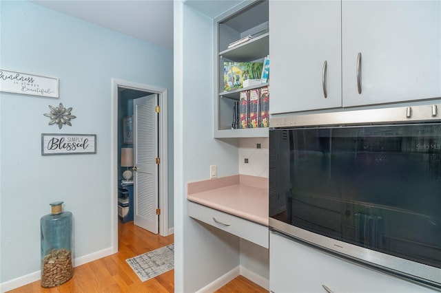 room details featuring hardwood / wood-style flooring, built in desk, and oven