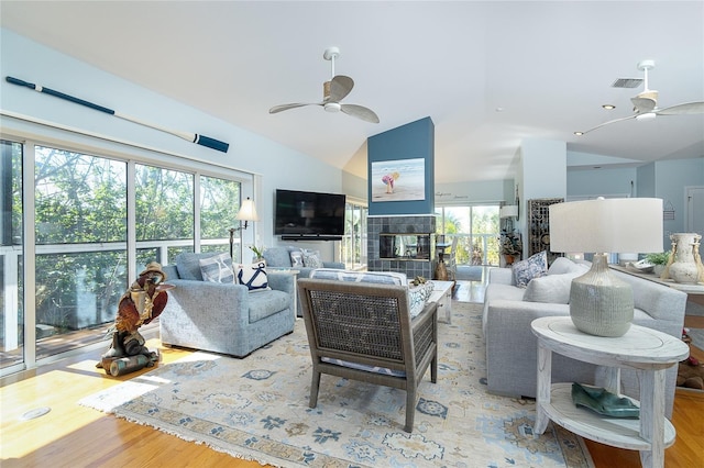 living room with lofted ceiling, a fireplace, light hardwood / wood-style floors, and ceiling fan