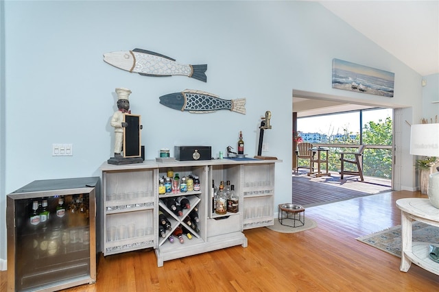 bar with hardwood / wood-style flooring, beverage cooler, and high vaulted ceiling