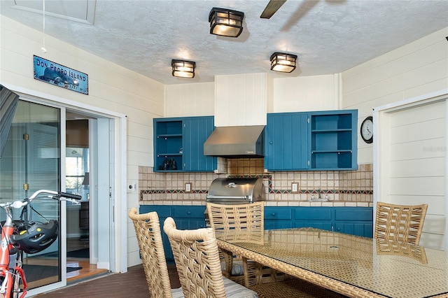 kitchen featuring blue cabinetry, dark hardwood / wood-style flooring, a textured ceiling, and backsplash