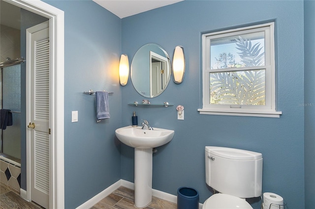 bathroom with wood-type flooring, sink, an enclosed shower, and toilet