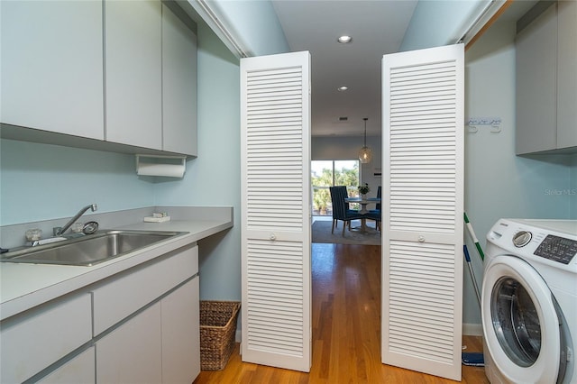 laundry area with cabinets, washer / dryer, sink, and light wood-type flooring