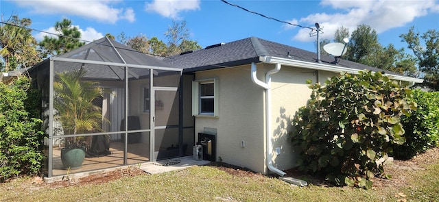 back of house featuring a yard and glass enclosure