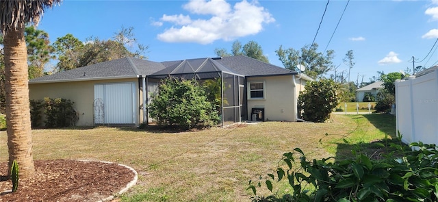 back of house with glass enclosure and a lawn