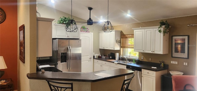 kitchen with appliances with stainless steel finishes, white cabinets, a kitchen bar, hanging light fixtures, and kitchen peninsula