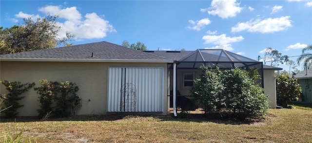 back of house with glass enclosure and a lawn