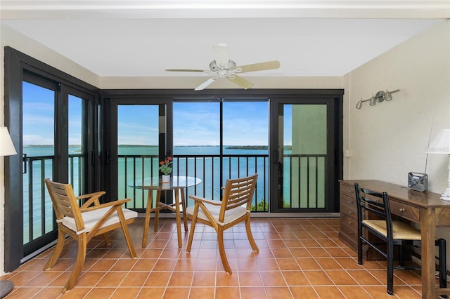 sunroom / solarium featuring a water view and ceiling fan