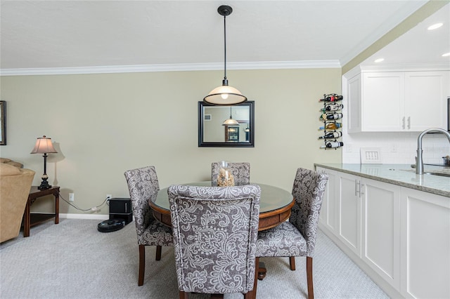 carpeted dining area with sink and crown molding