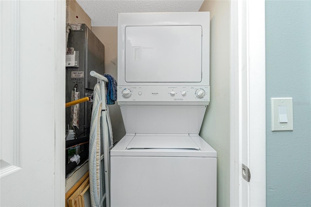 washroom featuring a textured ceiling and stacked washer / dryer