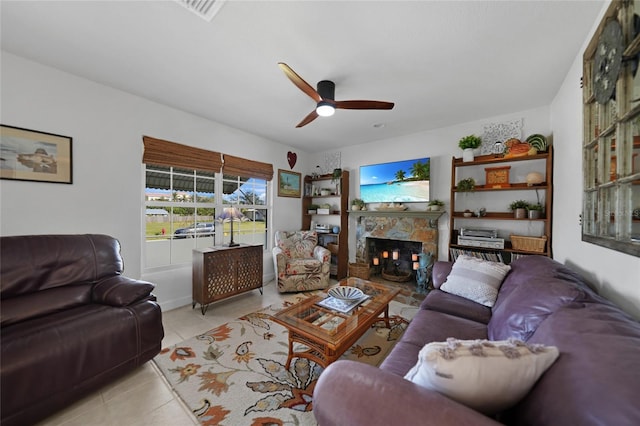 tiled living room with ceiling fan and a fireplace