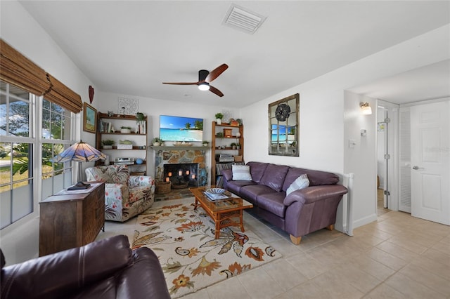 tiled living room featuring ceiling fan and a fireplace