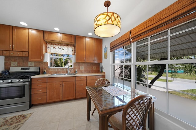 kitchen with pendant lighting, tasteful backsplash, sink, light tile patterned floors, and gas stove