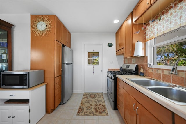 kitchen with appliances with stainless steel finishes, sink, light tile patterned floors, and decorative backsplash